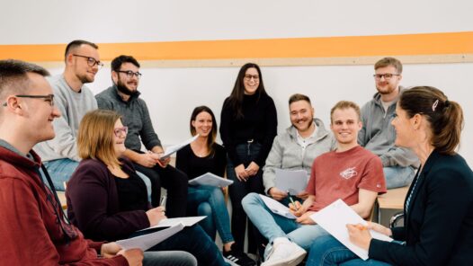 Eine Gruppe von jungen Leuten in einem Kreis sitzend und sich unterhalten.